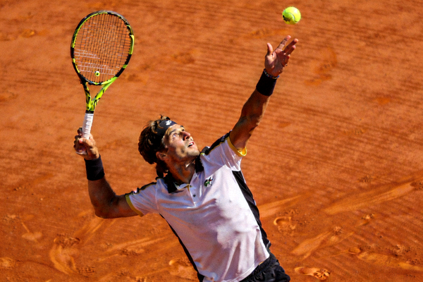 网球比赛发球动作 - 运动员在红土场上高高抛起网球，准备发球的优雅姿态